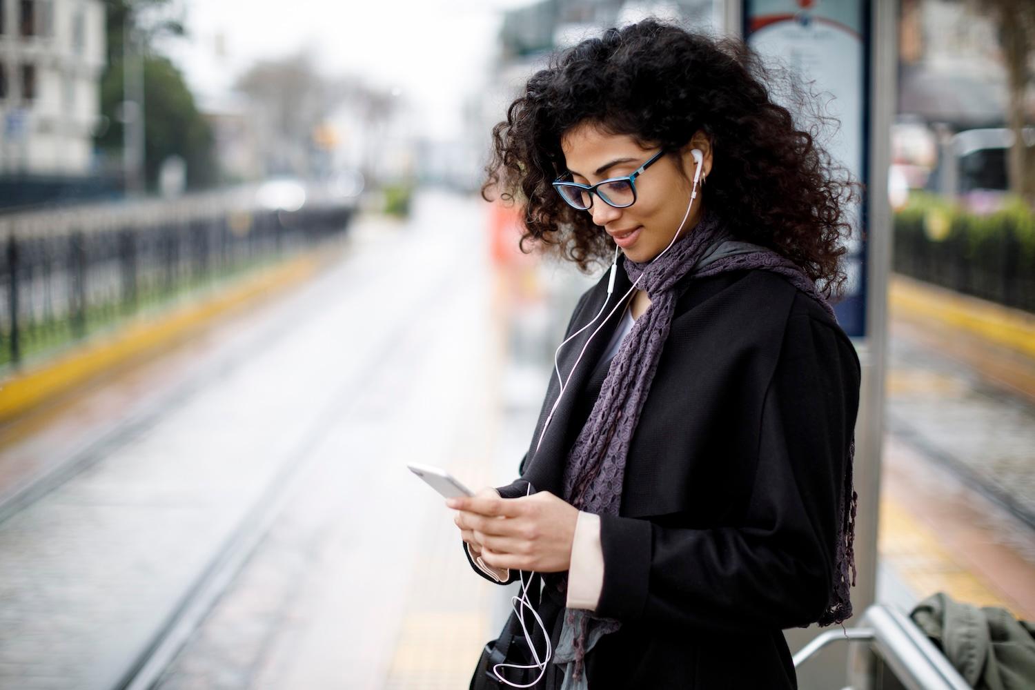 Woman with smartphone waiting for tram