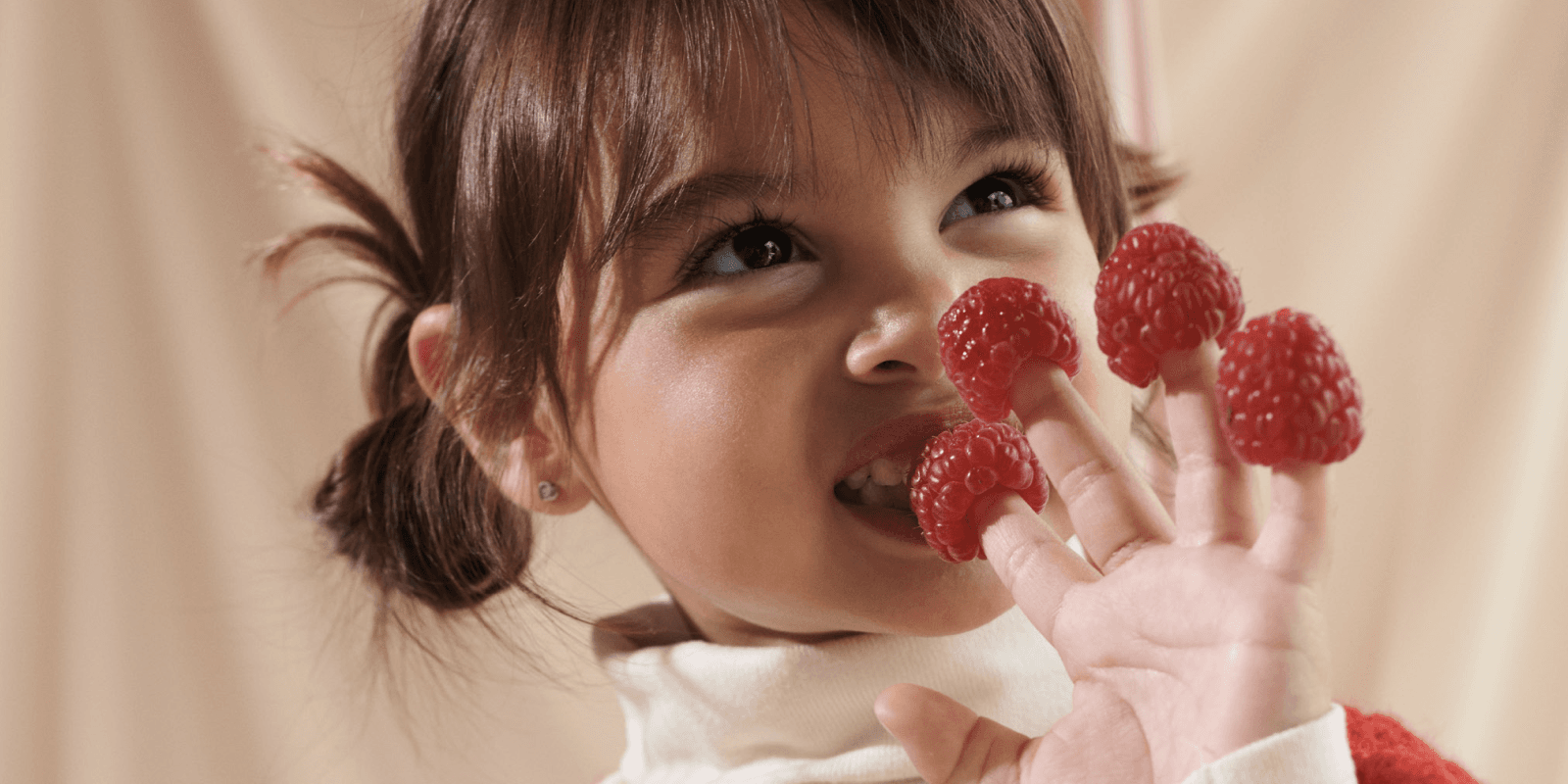 girl with raspberries on fingers