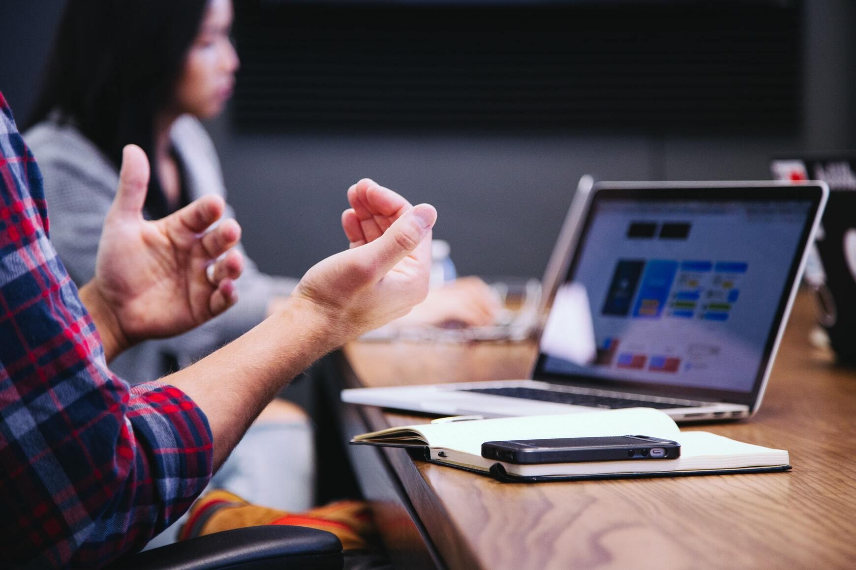 Person explaining with hands in front op computer