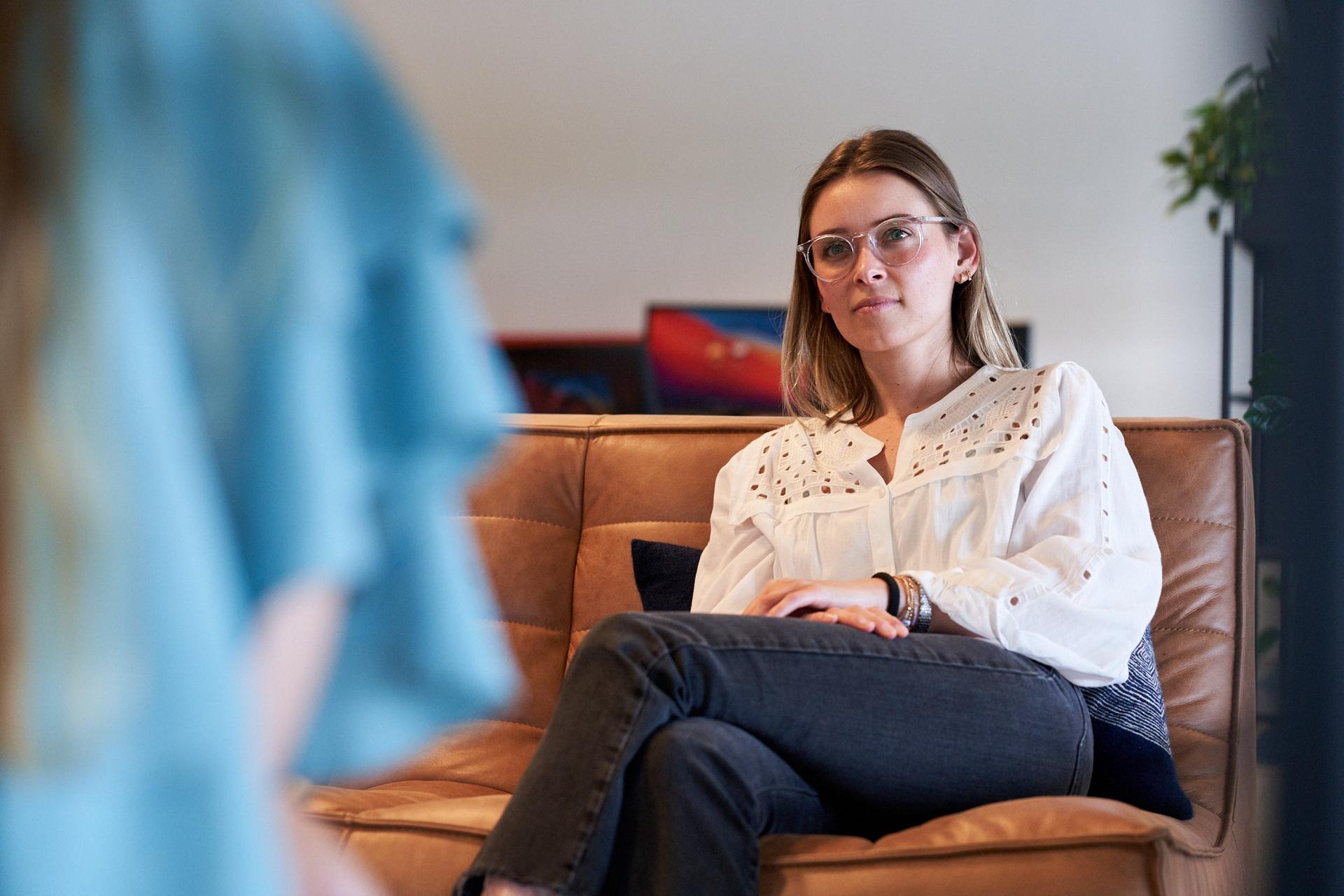 Woman sitting in couch listening to someone