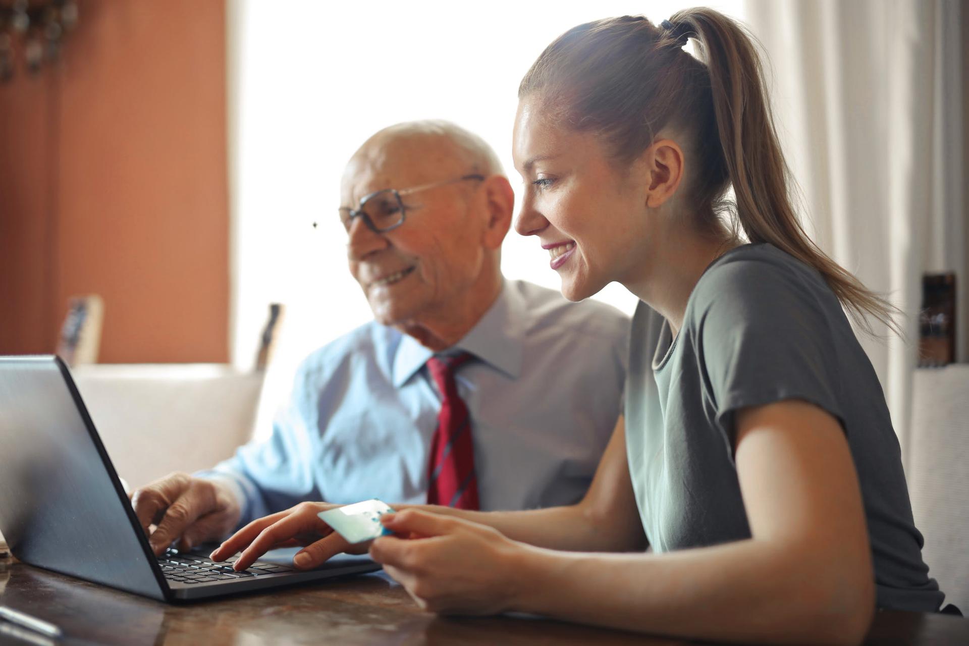 Woman helping older man with computer