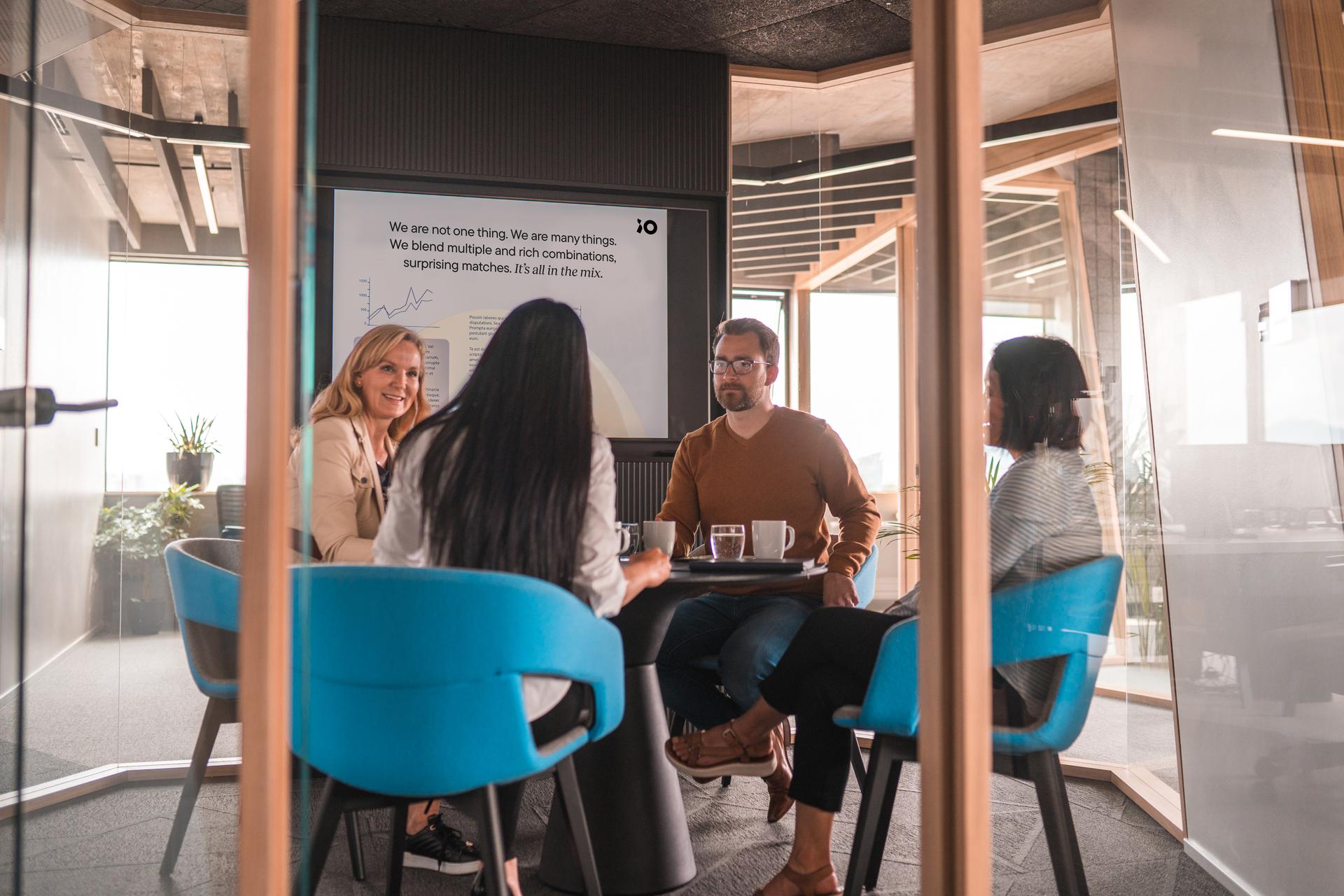 Team of four sitting around a meeting room table in an iO office space