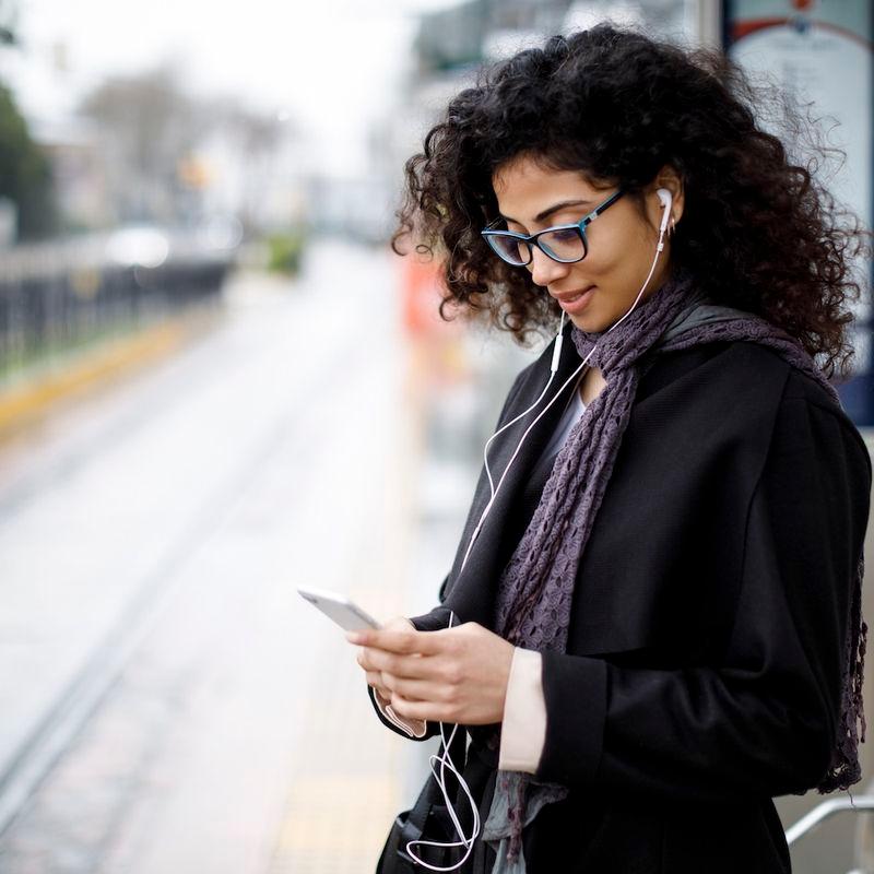 Woman with smartphone waiting for tram