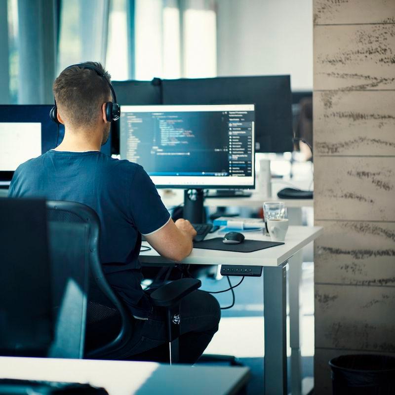 Male coding behind screen at office